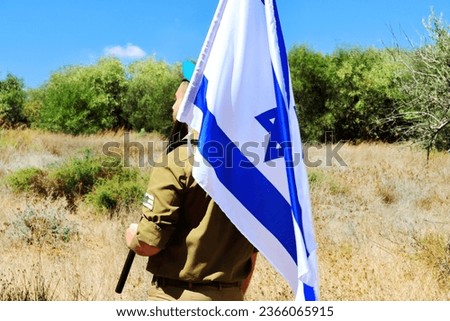 Israeli soldier with a large Israel Flag on his shoulder. Concepts photo: Israel Independence Day, IDF, Memorial Day, Jewish soldier