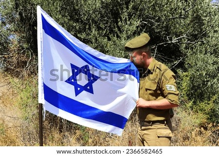 Israeli soldier with the rank of staff sergeant kisses the symbol of the Israeli state - Flag of Israel. Concept: Tzahal (IDF), holiday - Israel Independence Day, soldiers