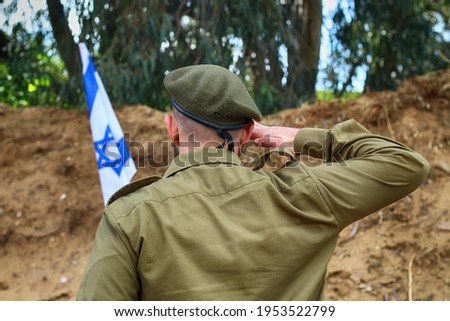 Israeli soldier salutes the flag of Israel on military exercise. Concept: Soldiers IDF (Israel Defense Forces, Tzahal),  IsraelI soldiers, Israeli Memorial day,  Independence Day Israel