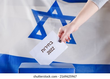 Israeli woman votes on election day. Close up of hand. Hebrew text Elections 2022 on Israel flag background. Israel heads for new election as fragile coalition collapses. - Shutterstock ID 2169625967