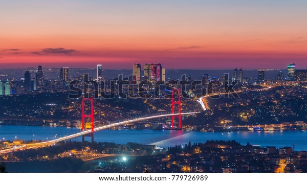 Istanbul city skyline cityscape time lapse from day to\
night view of bosphorus bridge (15th July Martyrs Bridge) and\
financial business center from Camlica hill. Traffic on the bridge\
and ship on