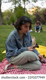 Istanbul, Turkey - 06.25.2022 : Smiling Young College Girl At Campus. She Is Sitting On Grass. University, Campus Life, Education Concept.