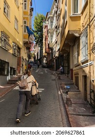 Istanbul, Turkey - August 13, 2019. Woman Pushing Stroller Up Narrow Street In Kadikoy District With Colorful Building Facades. Anatolian Side Is Older Settlement And Popular Touristic Destination.