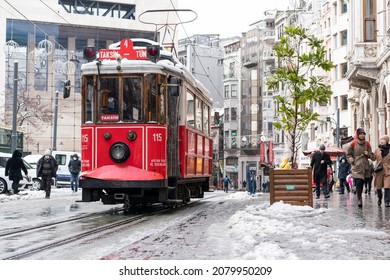 ISTANBUL TURKEY- FEBRUARY 15, 2021: Red nostalgic tram is moving on the Istiklal street in Beyoglu, Taksim, in winter day with snow. Cold snowy weather in Turkey. Flu season.