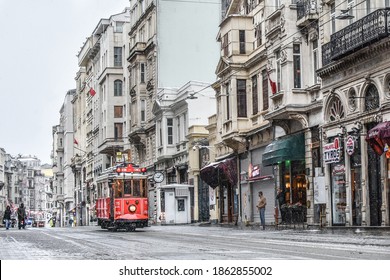 ISTANBUL TURKEY- FEBRUARY 24, 2019: Red nostalgic tram is moving on the Istiklal street in Beyoglu, Taksim, in winter day with snow. Cold snowy weather in Turkey. Flu season.