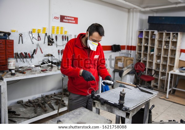 Istanbul, Turkey- January\
20, 2020. Labor is working in a car repair shop to fix on the car\
radiator parts.