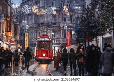 ISTANBUL TURKEY- March 11, 2022: Red nostalgic tram is moving on the Istiklal street in Beyoglu, Taksim, in winter day with snow. Cold snowy weather in Turkey.