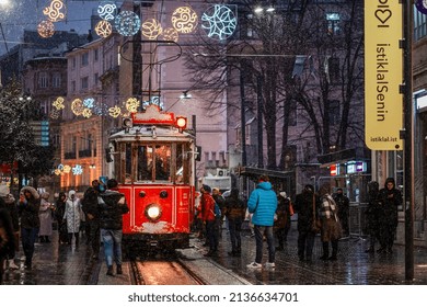 ISTANBUL TURKEY- March 11, 2022: Red nostalgic tram is moving on the Istiklal street in Beyoglu, Taksim, in winter day with snow. Cold snowy weather in Turkey.