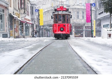 Istanbul Turkey - March 13, 2022: Red nostalgic tram is moving on the Istiklal street in Beyoglu, Taksim. Winter day with snow. Cold snowy weather in Turkey. Flu season.                 