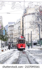 Istanbul Turkey - March 13, 2022: Red nostalgic tram is moving on the Istiklal street in Beyoglu, Taksim. Winter day with snow. Cold snowy weather in Turkey. Flu season.                 