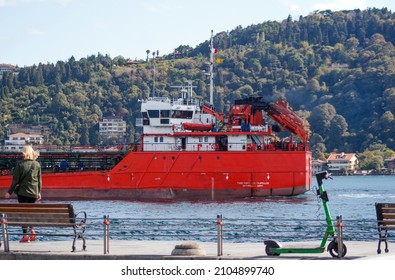 Istanbul Turkey, October 2021: Istanbul Landscape From European Shores Of Bosphorus, A Red Trading Vessel Passing Through Strait, People And Coastal Walk Path