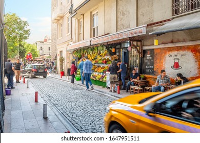 Istanbul, Turkey - September 21 2019: A Busy Street In The Galata Karakoy District Of Istanbul Turkey With Fruit Stand, Cafe, Tourists, Turks And A Speeding Taxi, In Istanbul Turkey.