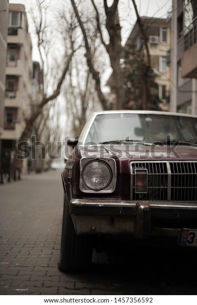 Istanbul,Kadikoy,Turkey-09-01-2018/ Half frame\
classic car and street appearing at depth. Tree lined street and\
cloudy day. Shallow depth of\
field.