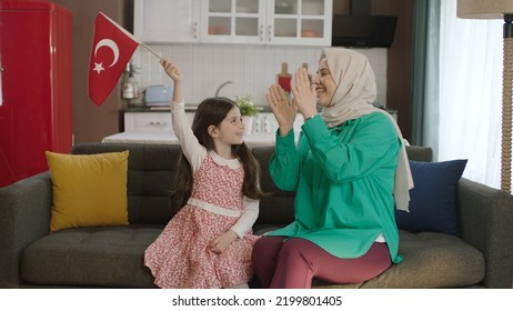 Istanbul,Turkey - 04.22.2022: A Turkish Family Is Smiling And Waving The Turkish Flag In The Living Room. Mother And Daughter In Hijab Celebrate Their National Holiday By Waving The Turkish Flag.