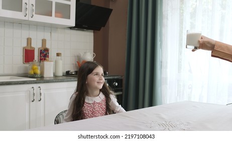 Istanbul,Turkey - 04.22.2022:She Gives Milk To Her Mother, Who Is Dressed In Hijab, To Drink. A Healthy Diet Is Important For A Child. The Girl Is Drinking Yogurt In The Kitchen And Licking Her Lips.