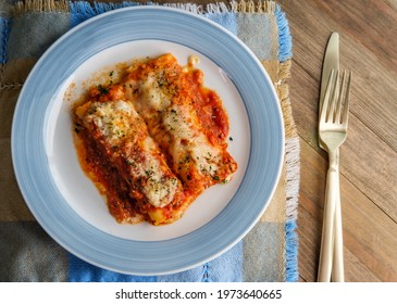 Italian American Baked Pasta Dish Stuffed Manicotti On Wooden Kitchen Table