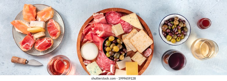 Italian antipasti or Spanish tapas panorama. Gourmet cold meat and cheese platter on a table, shot from the top with wine. A variety of appetizers. Mediterranean party with drinks - Powered by Shutterstock