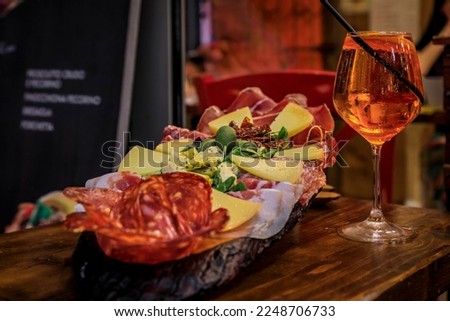 Italian antipasto platter with prosciutto, salami, cheese, olives served with a glass of aperol spritz cocktail at a restaurant in Florence, Italy