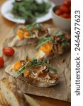 Italian appetizer bruschetta. Ready-made bruschetta made from bread, apricot, cheese and decorated with arugula and nuts lie on a wooden table and parchment. drinks for dinner nearby