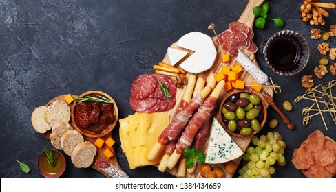 Italian appetizers or antipasto set with gourmet food on black table top view. Mixed delicatessen of cheese and meat snacks with red wine. - Powered by Shutterstock