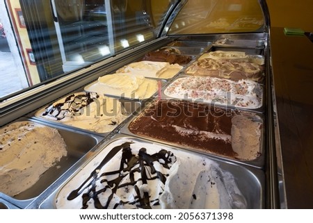Italian artisan ice cream (Gelato) manufacturing. Serving process in the shop. Icecream in stainless steel tray. Homemade assorted tastes. Close up. Selective focus.