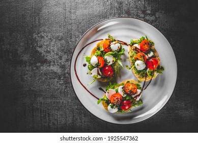 Italian bruschetta with roasted tomatoes, mozzarella cheese, balsamic vinegar and herbs on plate