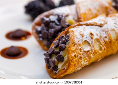 Italian cannoli on white plate with blackberries and chocolate chips