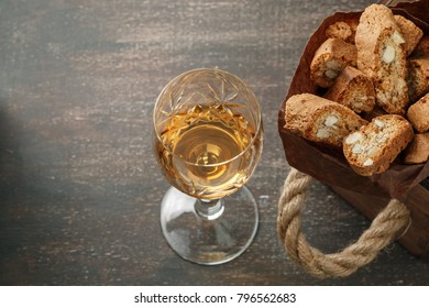 Italian cantucci biscuits and a glass of sweet Vin Santo wine over wooden background