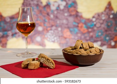 Italian cantucci biscuits over a red napkin and a glass of vin santo wine on background