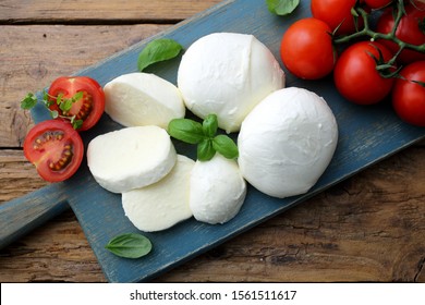 Italian cheese mozzarella with tomato on rustic kitchen table