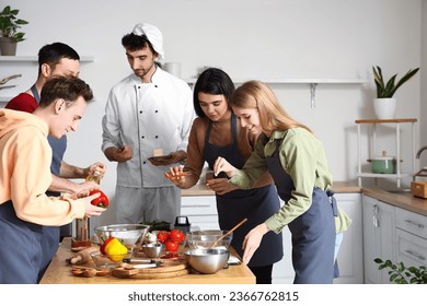 Italian chef with group of young people preparing pizza during cooking class in kitchen - Powered by Shutterstock