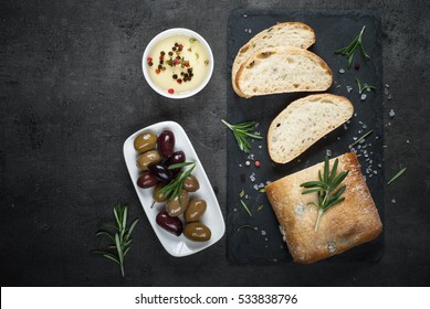 Italian Ciabatta Bread  On Black Slate Board With Herbs And Olives, Top View