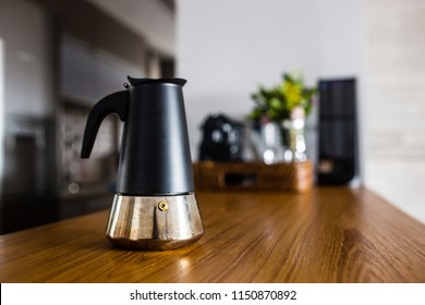 Italian Coffee Maker On Wooden Kitchen Counter With Interesting Perspective, With Cup In Focus And Blurred Background