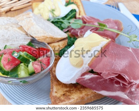 Italian cuisine dish, toasted toast in a toaster with poached eggs and Parma ham, salad of seasonal vegetables, tomatoes, cucumbers, crispbread Italian cuisine, poached eggs, Parma ham, seasonal vege