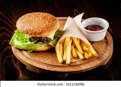 Italian cuisine. Homemade burger with beef chop, tomato, lettuce and sweet and sour sauce. French fries and ketchup. Serve on a wooden kitchen board. background image, copy space - Powered by Shutterstock