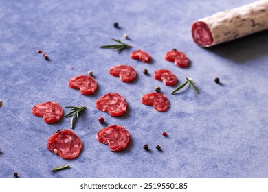 Italian delicatessen salami gourmet lover small pieces in the shape of hearts on blue background and rosmary with red black pepper and rosemary - Powered by Shutterstock