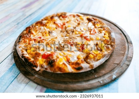 Italian delicious fresh hot mix baked seafood Tuna fish pizza with melting mozzarella cheese, hot spicy green pepper, sliced mushroom and corn bean serving on grey textured rustic background.