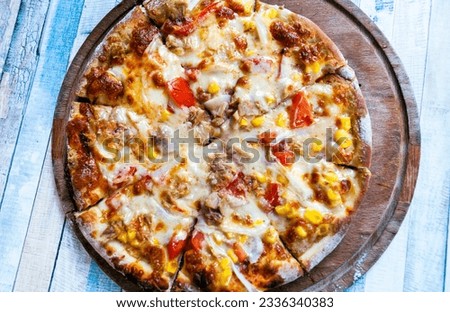 Italian delicious fresh hot mix baked seafood Tuna fish pizza with melting mozzarella cheese, hot spicy green pepper, sliced mushroom and corn bean serving on grey textured rustic background.