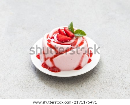 Italian dessert. Strawberry Panna Cotta with sauce, in the shape of a rose, on a plate. Light grey background