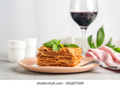 Italian Dinner. Meat Lasagna Decorated With Basil Leaves And Glass Of Red Italian Wine. Light Table. Copy Space.