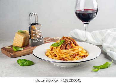 Italian Dinner With Red Wine. Egg Pasta Tagliatelle With Bolognese Sauce Made From Meat And Tomato Sauce, Parmesan Cheese. Light Grey Background.