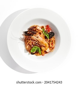 Italian Dish - Seafood Linguine Isolated On White Background. Pasta With Prawn, Mussels, Octopus,  Squid In Tomatoes Marinara Sauce. Seafood Pasta In Italian Restaurant Menu. Seafood On White Plate