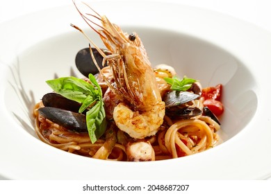 Italian Dish - Seafood Linguine Isolated On White Background. Pasta With Prawn, Mussels, Octopus,  Squid In Tomatoes Marinara Sauce. Seafood Pasta In Italian Restaurant Menu. Seafood On White Plate