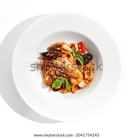 Italian dish - seafood linguine isolated on white background. Pasta with prawn, mussels, octopus,  squid in tomatoes marinara sauce. Seafood pasta in Italian restaurant menu. Seafood on white plate