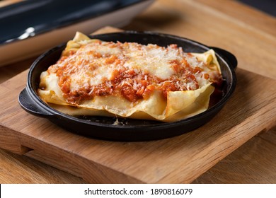 Italian dish. Traditional Italian lasagna cooked in a frying pan on the table, serving in a restaurant, menu food concept.