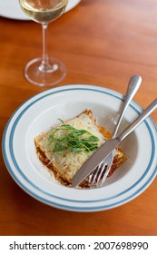 Italian dishes portion of lasagna served with herbs and glass of wine for dinner top view with copy space. dinner for one at the restaurant or cafe.