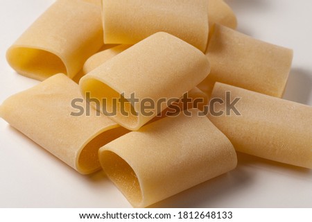 Italian dry raw pasta half paccheri calamarata macaroni, bronze die on white background  perspective  top view