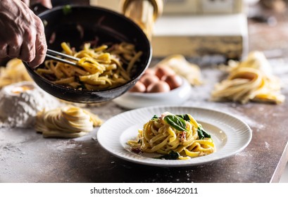 Italian egg spaghetti or fettuccine plated from a cooking pan by a professional chef. - Powered by Shutterstock