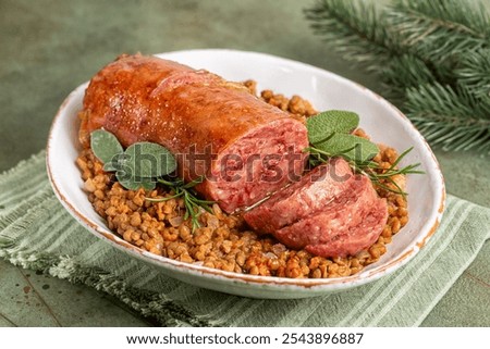 Italian Festive New  Year meal. Traditional cotechino con lenticchie or pork sausage with Lentils cooked with vegetables on a green table.