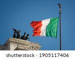 Italian flag with King Victor Emmanuel II equestrian monument in background. Piazza Venezia, Rome, Italy.